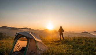Person har sovet i telt i naturen og ser solopgang